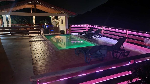 A pool area with a wooden deck, lounge chairs, and a poolside bar.