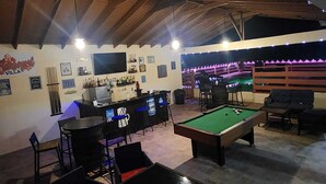 An indoor pool area with a bar, pool table, and seating.