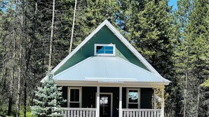 Eine kleine, eingeschossige Holzhütte mit Satteldach und einladender Veranda.