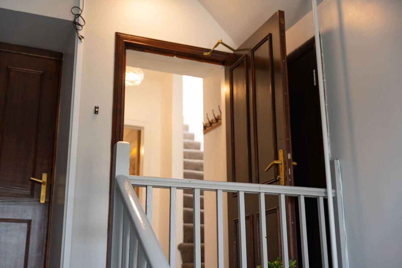 A staircase with a white handrail leading to a landing, flanked by wooden doors with brass handles.