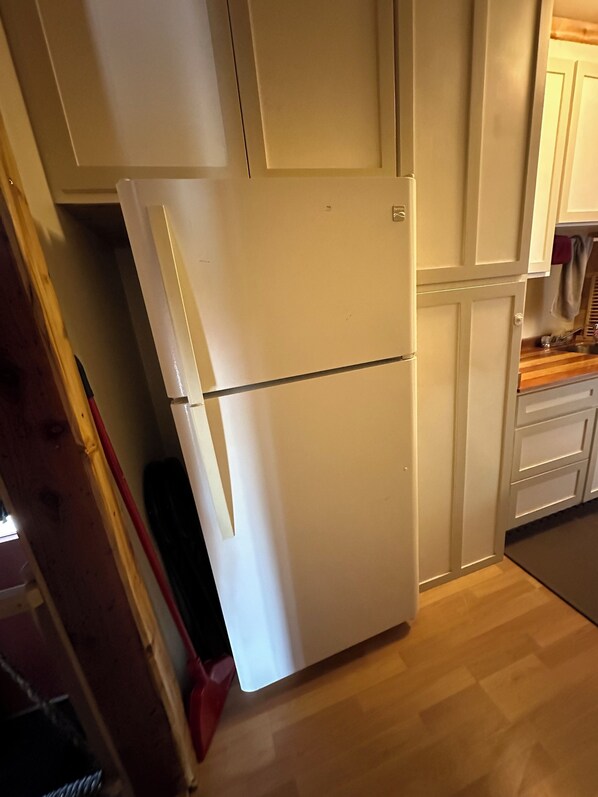 Una cocina con un refrigerador blanco, armarios de madera y una encimera de madera.