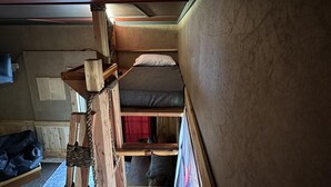 A compact, multi-level bunk bed room with wooden beams and a slanted ceiling.