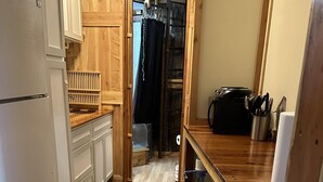 A kitchen with wooden cabinets, a refrigerator, a countertop with a water dispenser, and a dining area with a stool.
