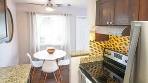Une cuisine compacte équipée d’une cuisinière, d’un four et d’un coin repas avec une table et des chaises.