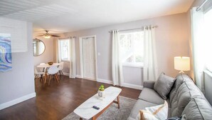 Un salon comprenant un canapé, une table basse, une table à manger avec des chaises et un ventilateur de plafond.