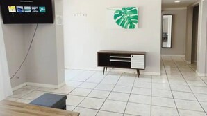 Una sala de estar moderna con un televisor de pantalla plana montado en la pared, una consola y una gran decoración de hoja verde.