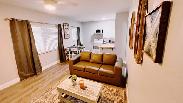 A living room with a brown sofa, a coffee table with a plant, and a ceiling fan.