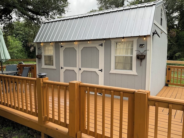 Situated on a wooden deck, this structure offers a tranquil retreat with a metal roof and wall-mounted lighting.
