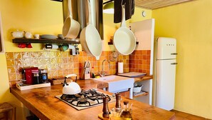 Een keuken met een gasfornuis, koffieapparaat en diverse keukengerei.
