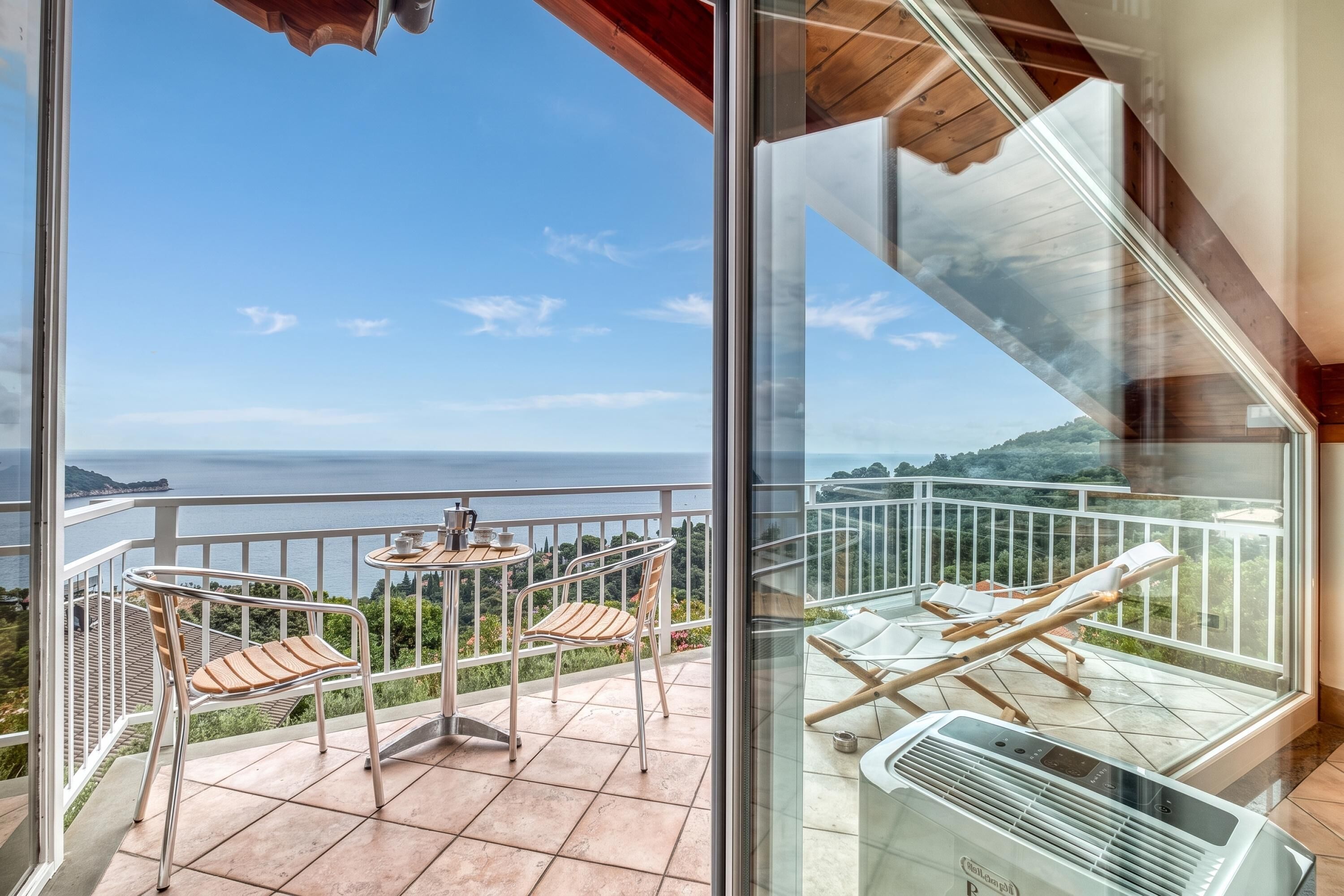 Un balcone con vista sul mare, un tavolo con sedie e una ventola a soffitto.