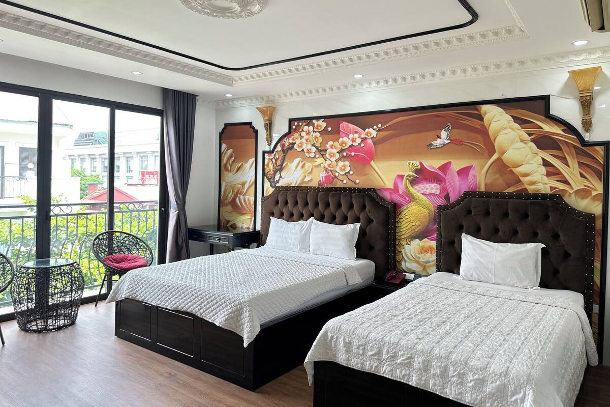 A hotel room with two beds, a large window, and a balcony.