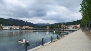 Un paseo ribereño con barcos amarrados, una barrera de cadena y edificios al fondo.