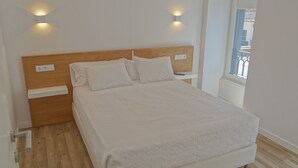 Una cama bien hecha con un cabecero de madera, dos mesitas de noche y una ventana con vistas.