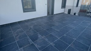 A building with a tiled patio, a door, and a window.