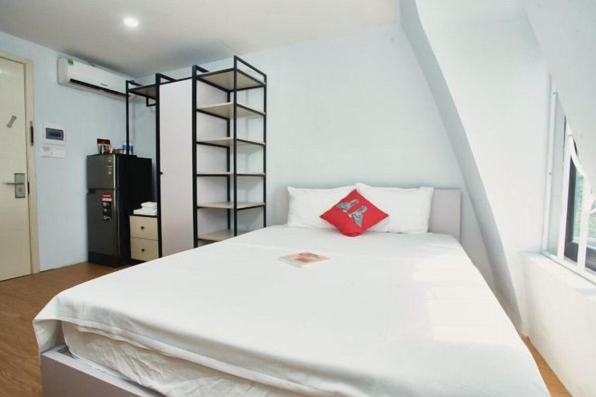 Ein Schlafzimmer mit einem Bett, einem roten Kissen, einem Kleiderschrank und einer eingebauten Regallösung.