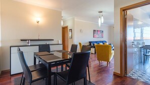 A modern living room with a dining area, featuring a sofa, chairs, and a coffee table. - GuestReady - Grandiose Getaway in Caniço (Caniço)