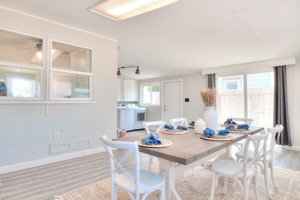 A dining area with a wooden table, white chairs, and blue napkins.