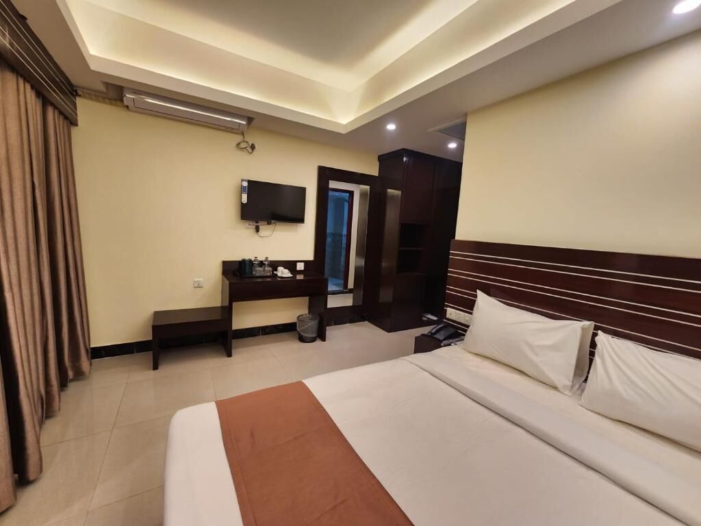 A hotel room with a bed, bedside table, TV, and a wardrobe.