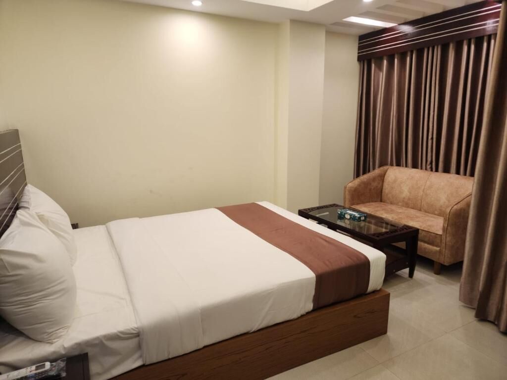 Une chambre d’hôtel avec un lit, un canapé, une table basse et des rideaux.