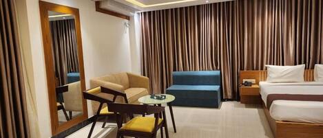 Ein Hotelzimmer mit Bett, Sofa, Sessel, kleinem Tisch und Spiegel.