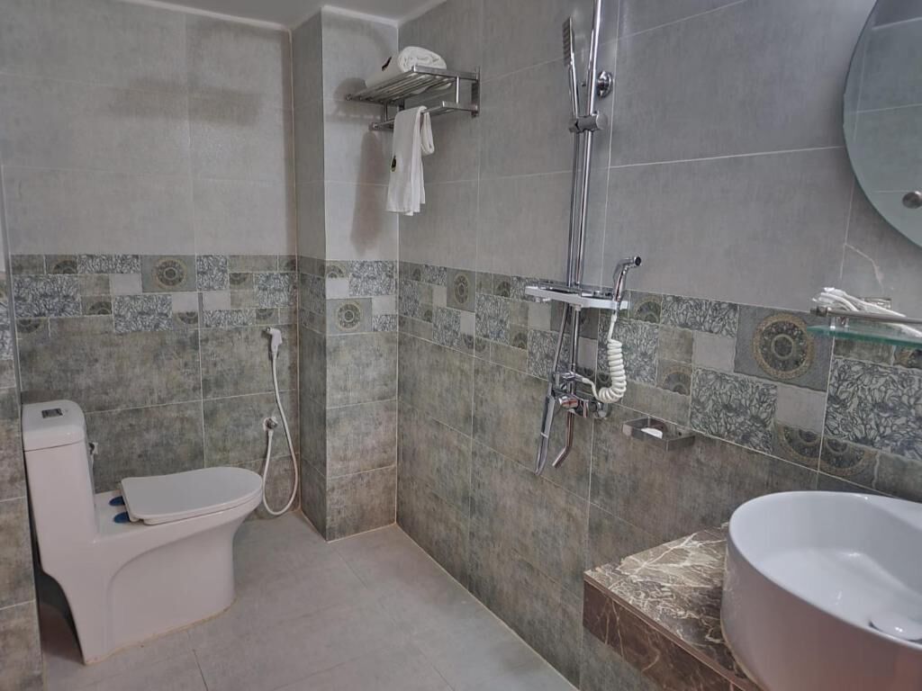 A bathroom with a toilet, a shower, and a sink.