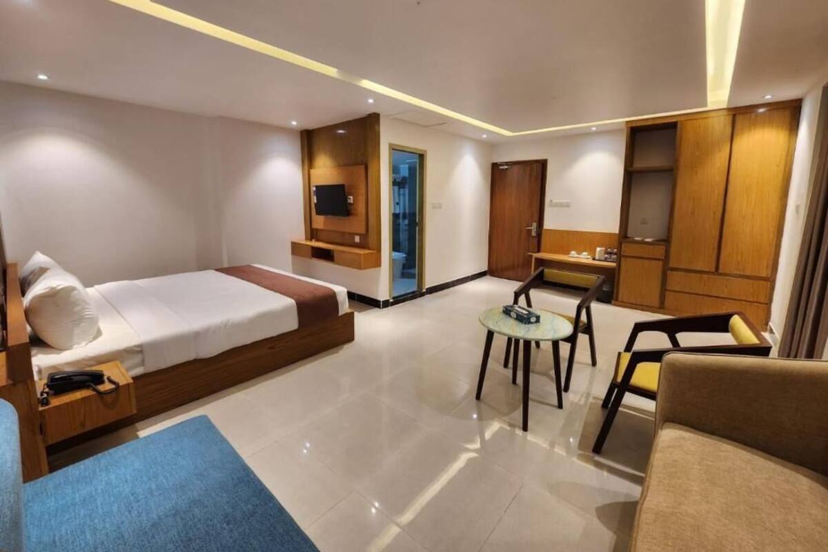 A modern hotel room with a bed, a desk, a chair, and a small table.