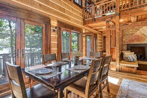 Enjoy meals in this cozy dining area with a large table for six, comfortable chairs, and a stone fireplace.