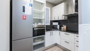 A modern kitchen with stainless steel appliances, white cabinetry, and a built-in oven. - Eixample 3BD Apartment with Private Terrace (Barcelona)