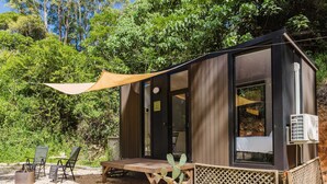 A small wooden cabin with a patio, a table, chairs, and a cactus plant. - Raspberry Spring Corner by Tiny Away (Clothiers Creek)