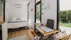 A bedroom with a bed, bedside table, and a view of the outdoors. - Raspberry Spring Corner by Tiny Away (Clothiers Creek)