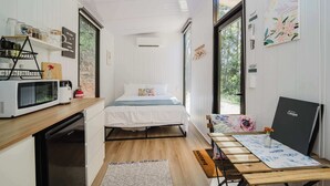 A compact room with a bed, kitchenette, and a desk with a computer. - Raspberry Spring Corner by Tiny Away (Clothiers Creek)