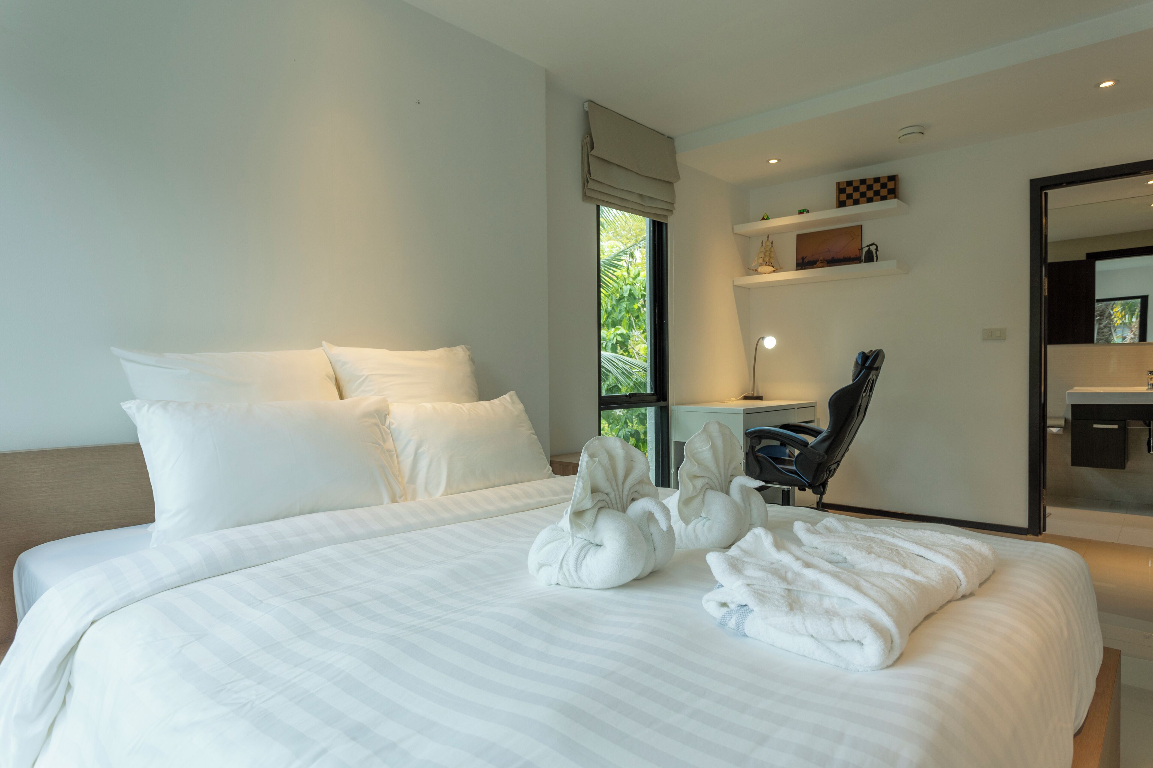 A modern hotel room with a large bed, a desk, and a chair.