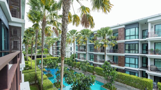 A modern hotel with multiple floors, a swimming pool, and lush greenery. - 100mBeachfront gym Swimming Pools c100 (Rawai)