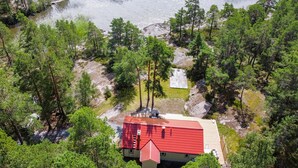 Une cabane au toit rouge, entourée d’une forêt dense et bordée d’un lac.