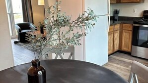 Una cucina moderna con mobili in legno, un frigorifero bianco e un'area pranzo con un tavolo rotondo e sedie.