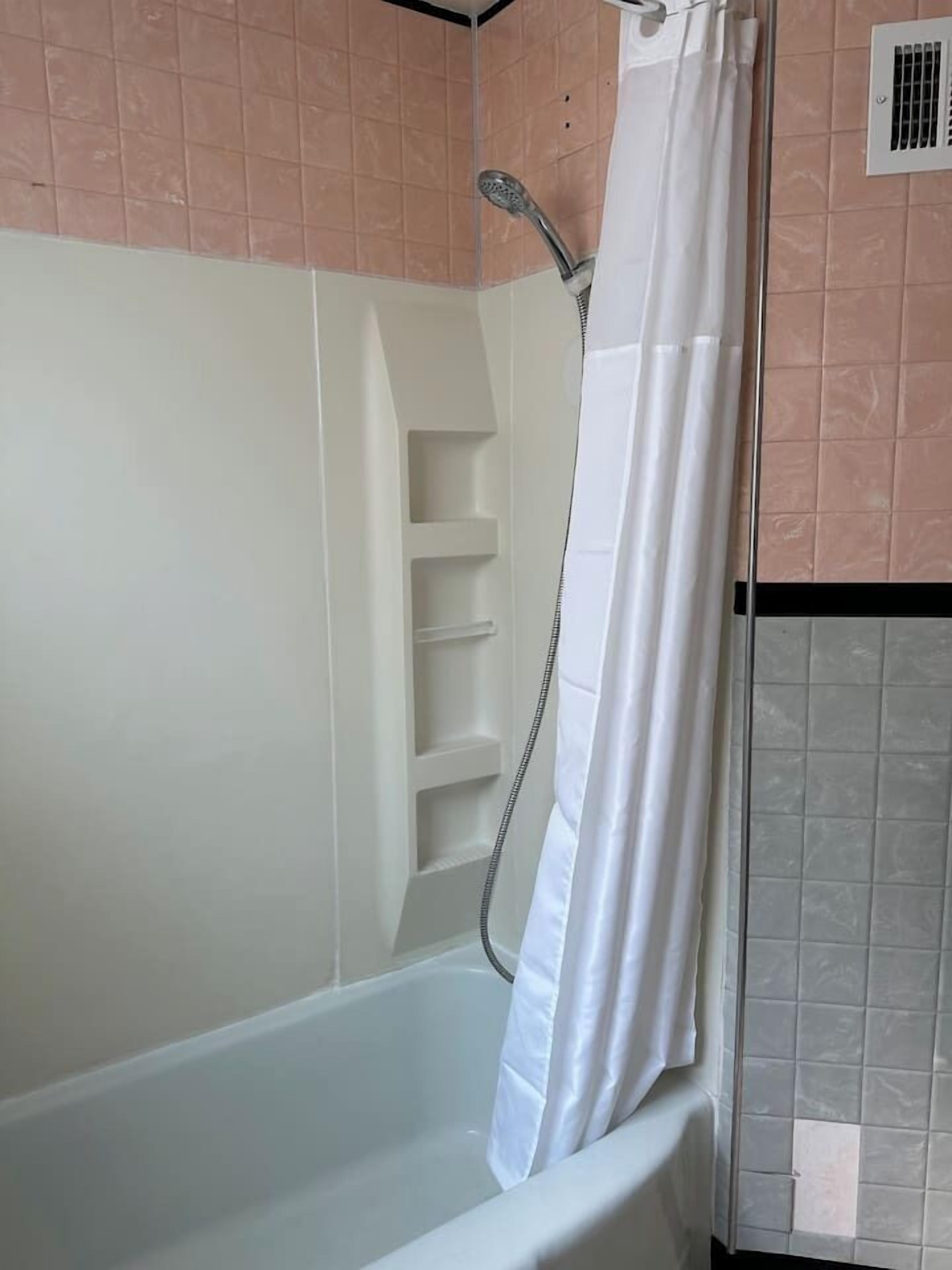 A bathroom with a bathtub, a shower, and a tiled wall.