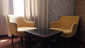 A room with two yellow armchairs and a dark glass coffee table. - Hotel Priydarshan (Kanpur)