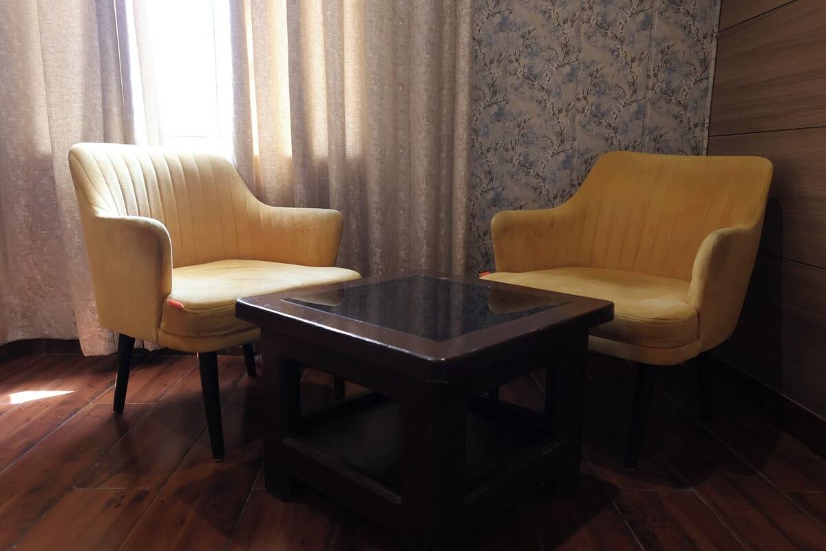 A room with two yellow armchairs and a dark glass coffee table.