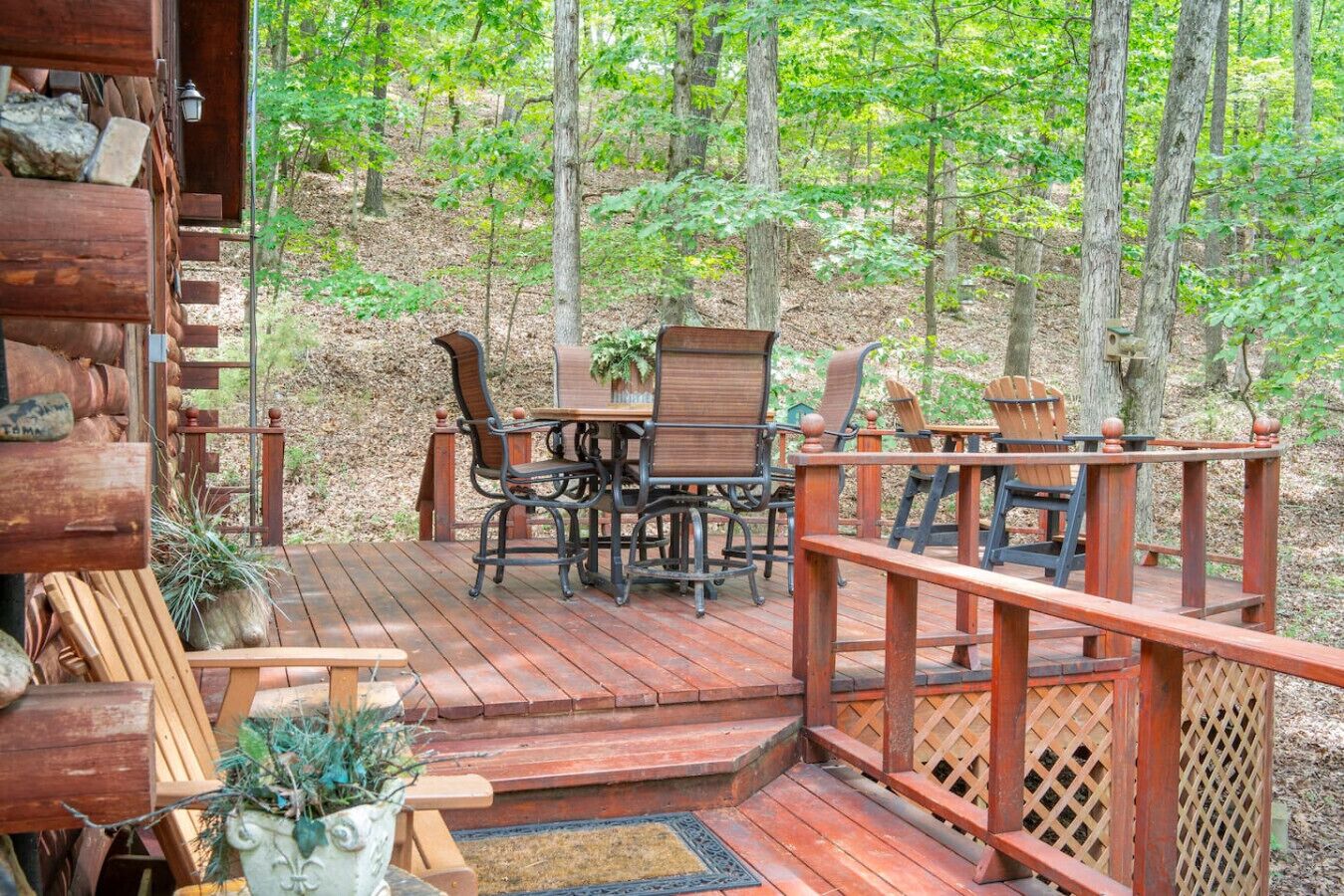 Eine Holzterrasse mit Tisch und Stühlen, umgeben von einem Wald.