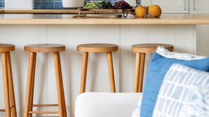 A modern kitchen with white cabinets, a blue tiled backsplash, and wooden stools. - Bluefin -  a house that sleeps 6 guests  in 3 bedrooms (Salcombe)