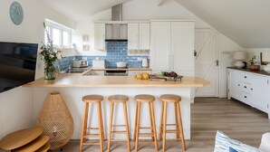A modern kitchen with a large island, bar stools, and a dining area. - Bluefin -  a house that sleeps 6 guests  in 3 bedrooms (Salcombe)