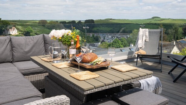 A rooftop terrace with a dining table set for two, featuring a loaf of bread, a bottle of wine, and a vase with flowers. - Bluefin -  a house that sleeps 6 guests  in 3 bedrooms (Salcombe)