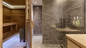 Une salle de bain moderne avec une douche, un banc en bois et une porte de douche en verre.