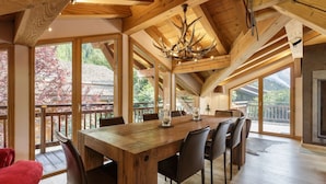 Un vaste espace dédié à la salle à manger, avec une grande table en bois, de nombreuses chaises et un lustre.