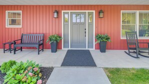 A red building with a grey door, two potted plants, a bench, and a rocking chair. - Newly Built Home Near Morrison Rockwood State Park (Morrison)