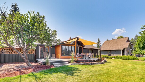 A modern house with a patio, a small deck, and a well-maintained lawn. - Deck & Mtn Views: Libby Home on Golf Course! (Libby)
