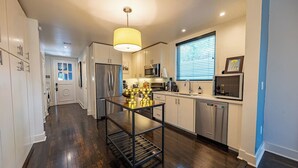 A modern kitchen with stainless steel appliances, a central island, and a window with blinds.