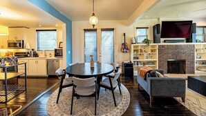 A modern kitchen with a dining area, a fireplace, and a living room with a TV.