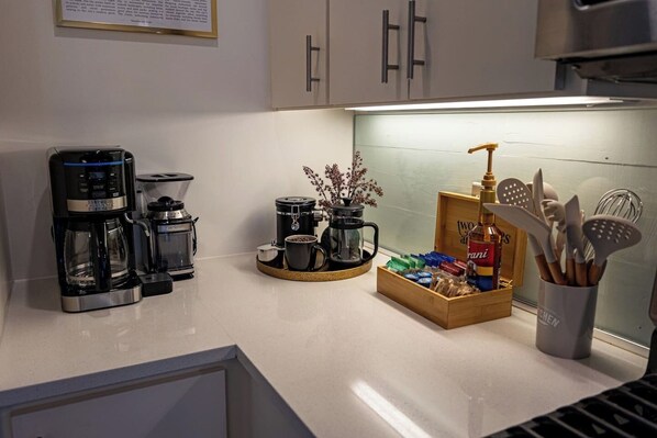 A kitchen with a coffee maker, a French press, and a box of coffee pods.