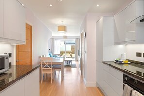 A modern kitchen with a microwave, a dining area with a table and chairs, and a view to the outside.